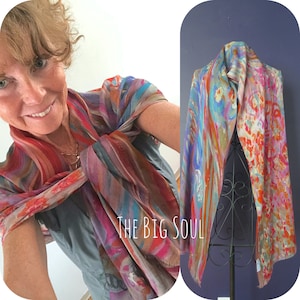 A colorful silk modal all season art scarf with abstract patterns in shades of blue, red, orange, pink. The scarf is displayed on a mannequin and also worn by a person.