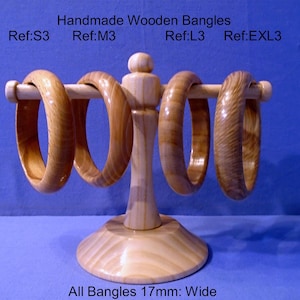 May include: Four handmade wooden bangles displayed on a light wood stand. The bangles are various shades of brown and are 1.7cm wide. The text "Handmade Wooden Bangles" is visible.