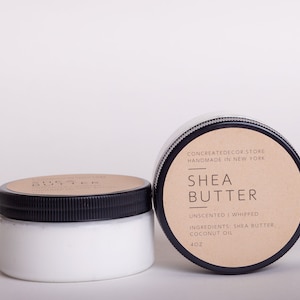 K&ouml;nnte beinhalten: Zwei 4 Unzen Gl&auml;ser mit unparf&uuml;mierter, geschlagenem Sheabutter mit einem braunen Papieretikett, auf dem "CONCREATEDECOR.STORE HANDMADE IN NEW YORK SHEA BUTTER UNSENTED WHIPPED INGREDIENTS: SHEA BUTTER, COCONUT OIL 4OZ" steht.