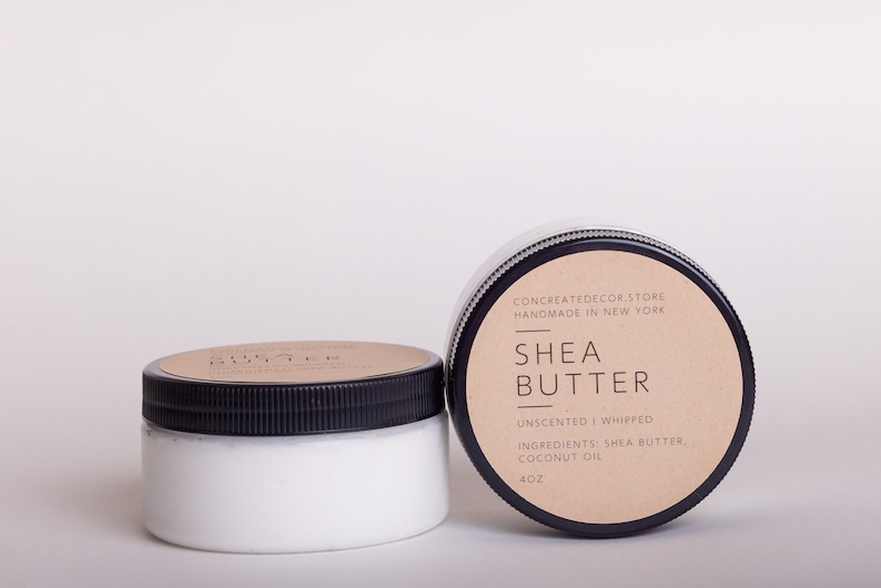 K&ouml;nnte beinhalten: Zwei 4 Unzen Gl&auml;ser mit unparf&uuml;mierter, geschlagenem Sheabutter mit einem braunen Papieretikett, auf dem "CONCREATEDECOR.STORE HANDMADE IN NEW YORK SHEA BUTTER UNSENTED WHIPPED INGREDIENTS: SHEA BUTTER, COCONUT OIL 4OZ" steht.