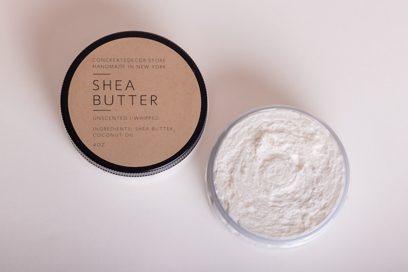 K&ouml;nnte beinhalten: Ein kleines Glas ungedufteter, geschlagene Sheabutter mit einem braunen Etikett, auf dem "CONCREATEDECOR.STORE HANDMADE IN NEW YORK SHEA BUTTER UNSCENTED I WHIPPED INGREDIENTS: SHEA BUTTER, COCONUT OIL 4OZ" steht.