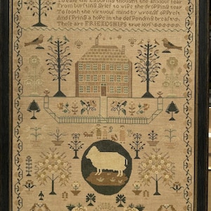 Puede incluir: Muestra antigua enmarcada con un diseño detallado. La obra de arte presenta una casa central, árboles, pájaros y una oveja en un marco circular. La pieza incluye texto sobre la amistad y está fechada en 1847. La paleta de colores es principalmente beige, marrón y verde.