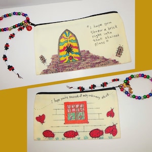 May include: Two cream-colored zippered pouches with beaded wrist straps. One features a stained glass window illustration with the text "I hope you threw a brick right into that stained glass" and two small rectangular figures. The other shows a red window, ladybugs, and the text "I hope you're scared of only ordinary shit..."