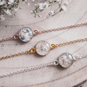 Könnte beinhalten: Drei zarte Armbänder mit kleinen runden Glasanhängern, die mit weißem Sand gefüllt sind. Die Armbänder sind aus Silber-, Gold- und Roségoldketten gefertigt.