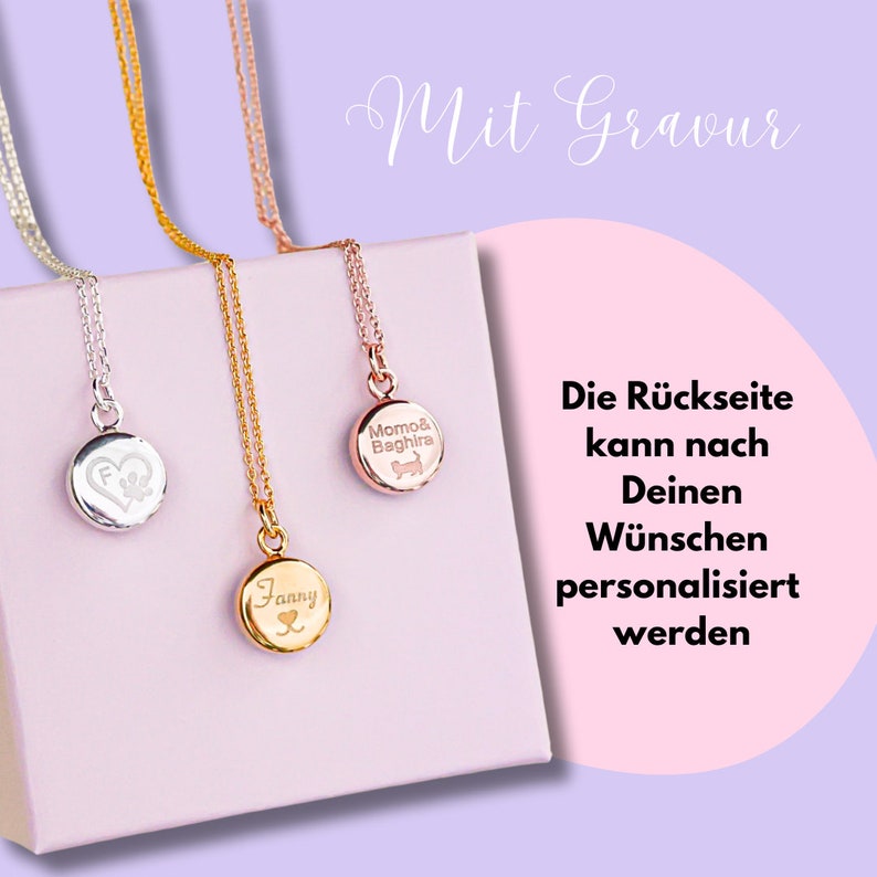 Op de afbeelding: Drie gouden kettingen met ronde hangers. De hangers zijn gegraveerd met de namen "Fanny", "Momo & Baghira" en een hart met een pootprint. De tekst "Mit Gravur" is in cursief boven de kettingen geschreven. De tekst "Die R&uuml;ckseite kann nach Deinen W&uuml;nschen personalisiert werden" is onder de kettingen geschreven.