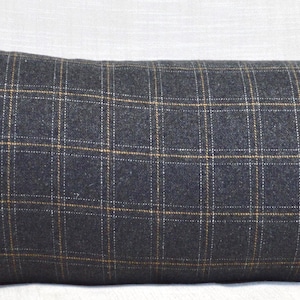 May include: A long, rectangular pillow with a gray and brown plaid pattern. The pillow is made of a soft, textured fabric.