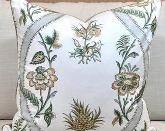 May include: A white cushion with a green and brown floral pattern. The cushion has a grey border with a decorative pattern.