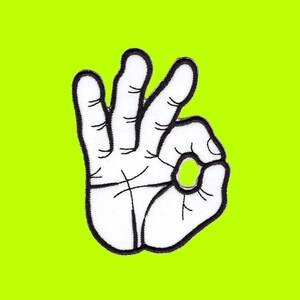 May include: Embroidered patch featuring a white hand making the "OK" gesture, outlined in black. The patch is set against a vibrant, neon green background. The design is simple and bold, suitable for various applications.