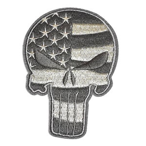 Op de afbeelding: Geborduurde patch met een schedelontwerp met een Amerikaanse vlag. De schedel is weergegeven in grijstinten en zwart, met de sterren en strepen van de vlag geïntegreerd. De patch heeft een grijze rand.