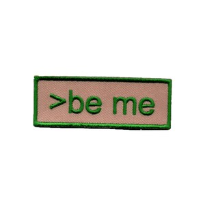 May include: A pink and green embroidered patch with the text ">be me".