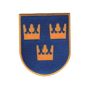 May include: A blue and gold embroidered patch with three gold crowns on a blue shield. The crowns have a clover design in the centre.