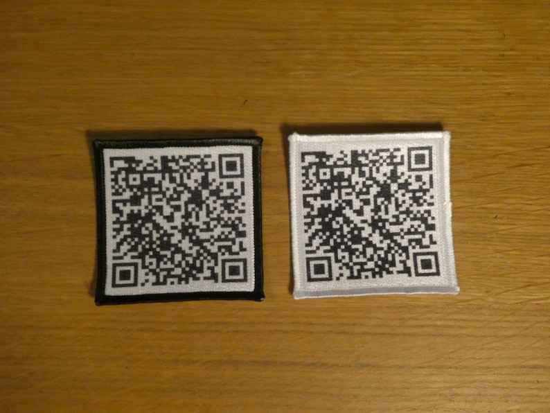 May include: Two square fabric patches with black and white QR codes. The patch on the left has a black border and a white QR code. The patch on the right has a white border and a black QR code.