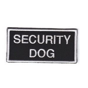 May include: Black and white embroidered patch with the text "SECURITY DOG" in white lettering.