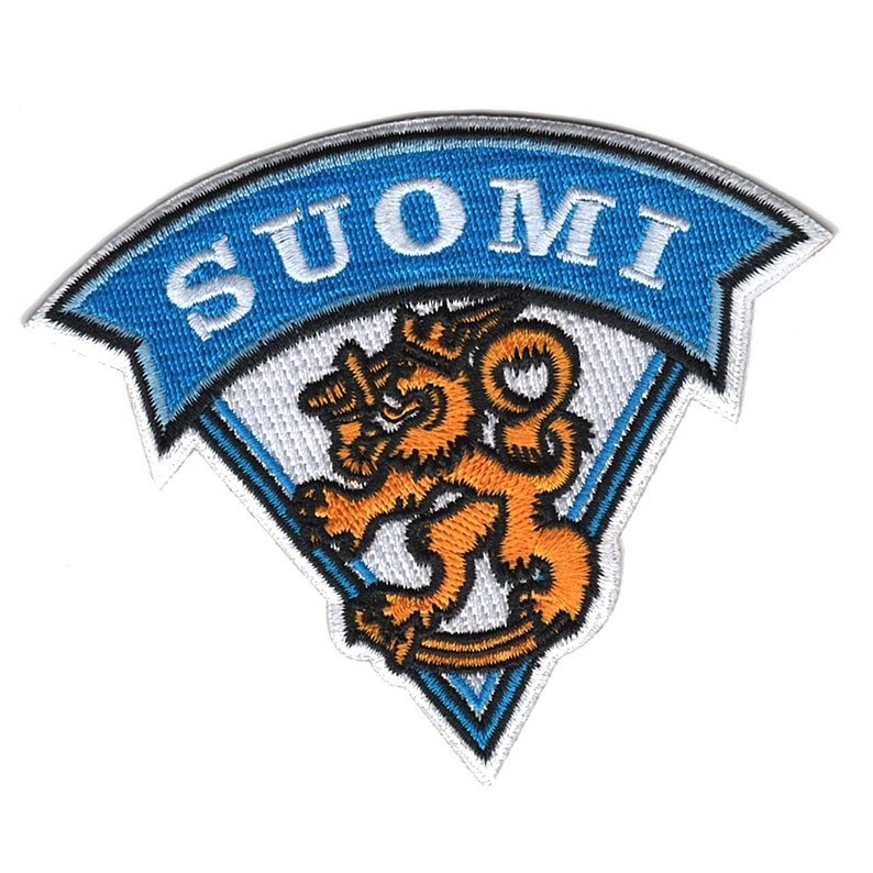 Puede incluir: Un parche bordado con un dise&ntilde;o triangular azul y blanco. El parche presenta un le&oacute;n blanco con una melena y cola naranja, y la palabra "SUOMI" en letras blancas sobre una pancarta azul.