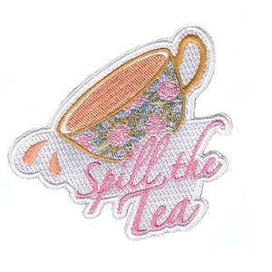 May include: Embroidered patch with a teacup design. The teacup has a floral pattern in pink and blue, and a gold handle. The phrase "Spill the Tea" is written in pink script below the cup, all outlined in white.