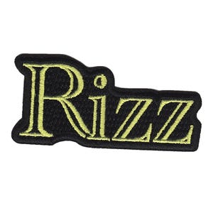 Könnte beinhalten: Ein schwarzer gestickter Aufnäher mit dem Wort "Rizz" in gelbem Garn.