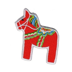 Pode incluir: Um cavalo Dala bordado em vermelho e branco, um brinquedo de madeira tradicional sueco, com detalhes verdes, azuis e amarelos.