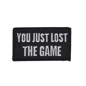 Könnte beinhalten: Schwarzer gestickter Aufnäher mit weißem Text, der "You Just Lost The Game" lautet.