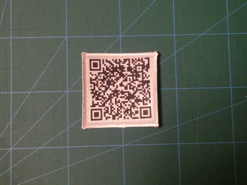 May include: A white fabric patch with a black and white QR code printed on it.