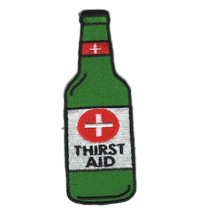 Könnte beinhalten: Grüne Glasflasche mit einem weißen Etikett, auf dem "THIRST AID" und ein rotes Kreuz in einem Kreis steht. Die Flasche hat ein rotes und weißes Kreuz oben.
