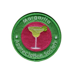 May include: Circular embroidered patch with a green border and the text "Margarita Appreciation Society." The centre has a pink circle with a yellow margarita cocktail and lime. Ideal for adding to clothing or bags.