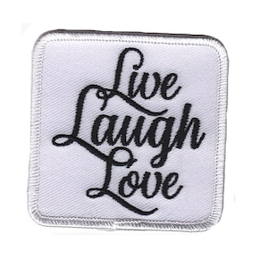 Op de afbeelding: Witte geborduurde patch met zwarte tekst "Live Laugh Love".