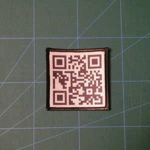 May include: A black and white QR code patch with a black border. The patch is made of fabric and has a white background.