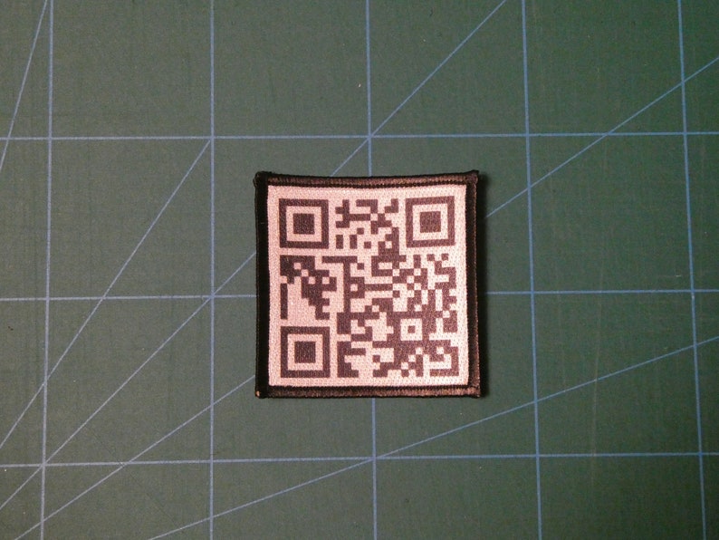 May include: A black and white QR code patch with a black border. The patch is made of fabric and has a white background.