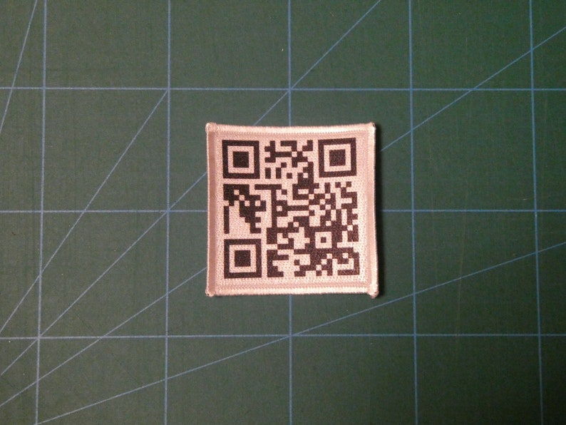 May include: A white fabric patch with a black and white QR code printed on it.