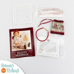 Pode incluir: Um conjunto de acessórios para boneca Felicity Merriman incluindo um lenço branco com borda de renda, uma bolsa floral com cordão, um colar de contas vermelhas, um cartão de informações históricas e uma fita, embalados em sacos plásticos.