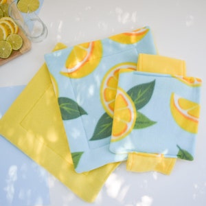 May include: Three yellow and blue fleece pet beds with a lemon print. The beds are layered on top of each other. The top bed is a smaller size and has a yellow border.