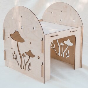 Puede incluir: Una casa de juegos de madera con forma de hongo con una ventana recortada y un peque&ntilde;o estante. La casa de juegos est&aacute; pintada en un color madera claro y tiene un dise&ntilde;o caprichoso.