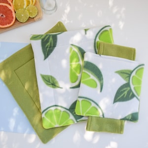 May include: Four green and white fabric coasters with a lime pattern. The coasters are made of a soft, plush material and are perfect for protecting surfaces from heat and spills.