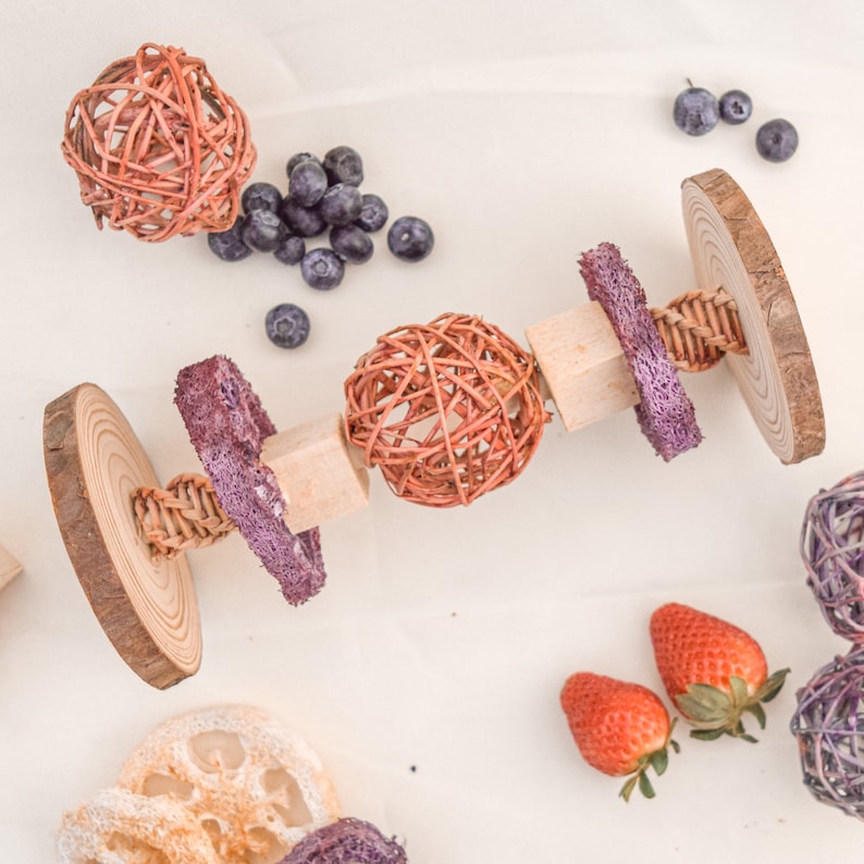 May include: A wooden toy for pets with a variety of textures, including woven balls, wood, and textured fabric. The toy is designed to be interactive and engaging for pets.