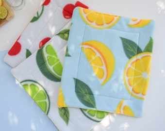 May include: Three fleece pet beds with fruit patterns. One is white with red cherries, another is white with green limes, and the third is light blue with yellow lemons. Each bed has a stitched border and a quilted design.