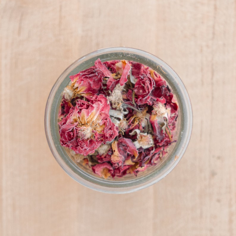 Rose petals in glass jar on wooden cutting board