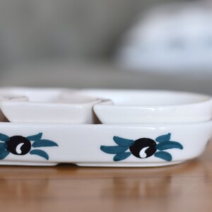 May include: White ceramic serving dish with four individual bowls. The dish has a blue and black olive design.