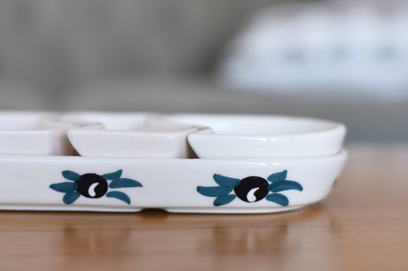 May include: White ceramic serving dish with four individual bowls. The dish has a blue and black olive design.