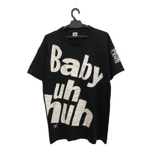 May include: Black t-shirt with white text that reads "Baby uh huh" in a bold, stylized font.