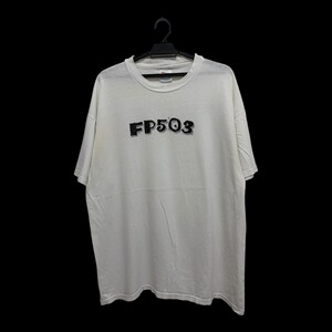Puede incluir: Una camiseta blanca con el texto "FP503" en negro, con una fuente texturizada. La camiseta está colgada de una percha negra sobre un fondo negro. La camiseta parece estar hecha de un material suave y cómodo.