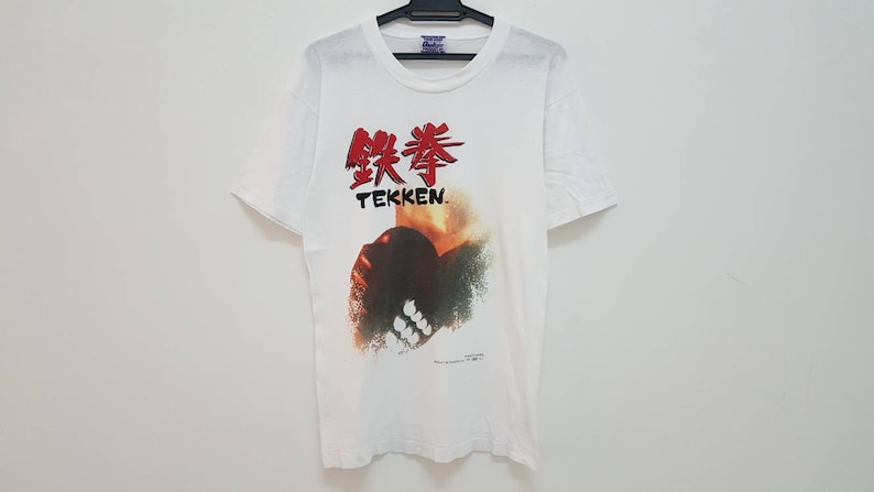 May include: White t-shirt with a red and black graphic of a fist and the text "鉄拳 TEKKEN."
