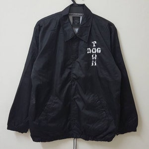 Könnte beinhalten: Schwarze Nylonjacke mit einem weißen gestickten Kreuz und dem Text "T DOG TOWN" auf der Rückseite.