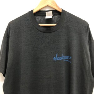 May include: Black short-sleeved t-shirt with a blue "Jackson" graphic on the front.