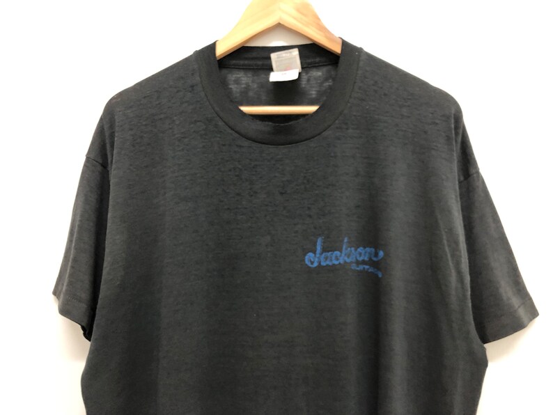 May include: Black short-sleeved t-shirt with a blue "Jackson" graphic on the front.