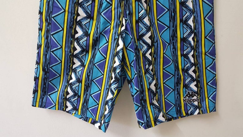 May include: Blue and yellow patterned swim trunks with the Kappa logo on the right leg.