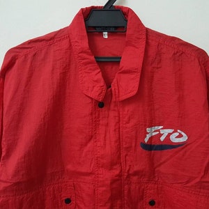May include: A red nylon jacket with a blue and white logo that says "FTO".