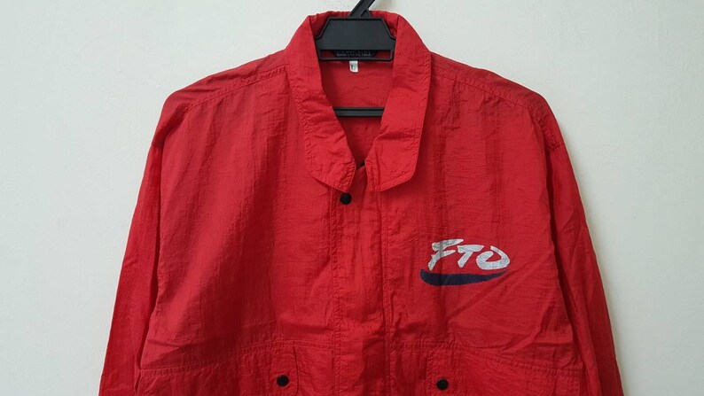 May include: A red nylon jacket with a blue and white logo that says "FTO".