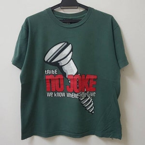 May include: A green t-shirt featuring a white screw graphic and the text "tRiBe NO JOKE we know where you live" in red.