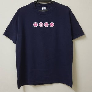 Könnte beinhalten: Ein marineblaues T-Shirt mit einem weißen und rosafarbenen Logo, auf dem "YOGA" in einem Kreis steht.