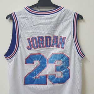 May include: White basketball jersey with blue and red trim. The back of the jersey has the name "JORDAN" and the number "23" in a blue and white design.
